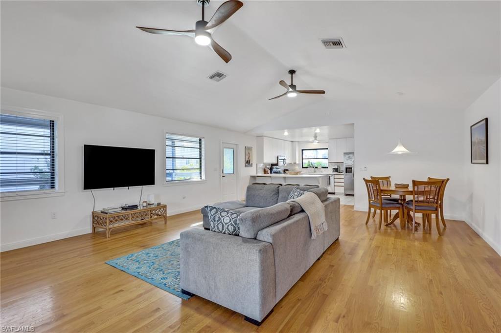 Living room featuring lofted ceiling, light wood finished floors, and a ceiling fan