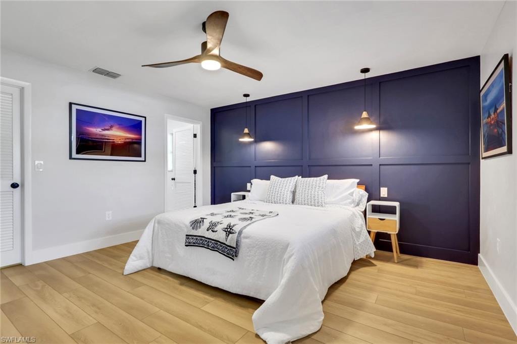Bedroom 1- with a decorative wall, wood finished floors, a ceiling fan, and an accent wall