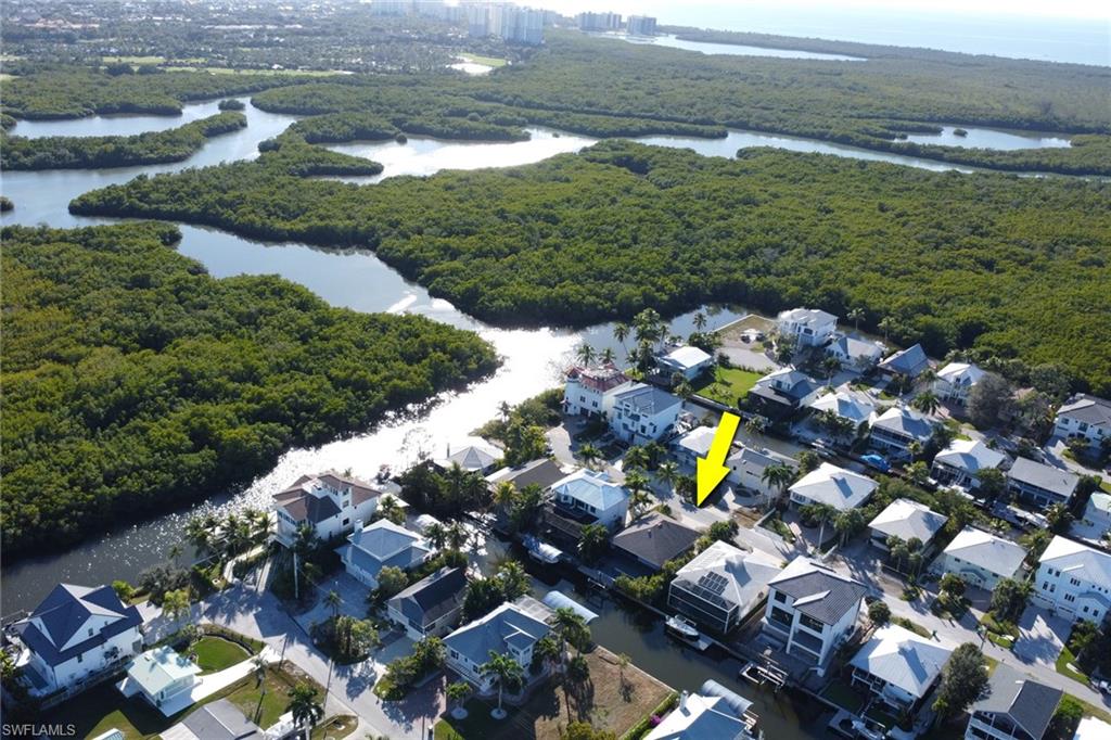Aerial view of property's location with a nearby body of water and a heavily wooded area