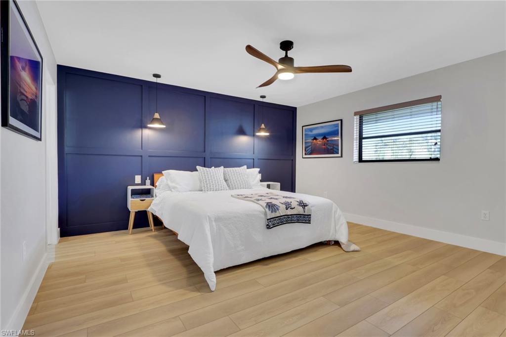 Bedroom 1- with a decorative wall, a ceiling fan, light wood-type flooring, and an accent wall