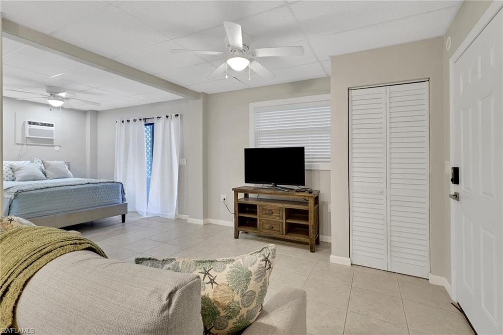 1/1 Efficiency-Bedroom featuring light tile patterned flooring, a paneled ceiling, a ceiling fan, and a closet