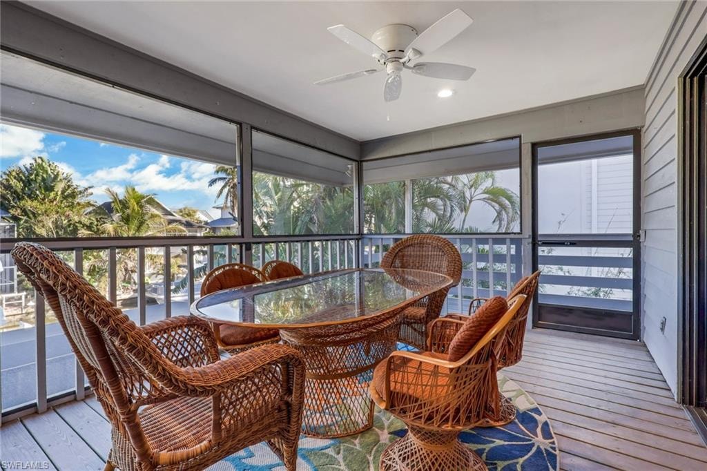 Sunroom with hardwood / wood-style floors, a ceiling fan, and outdoor dining area