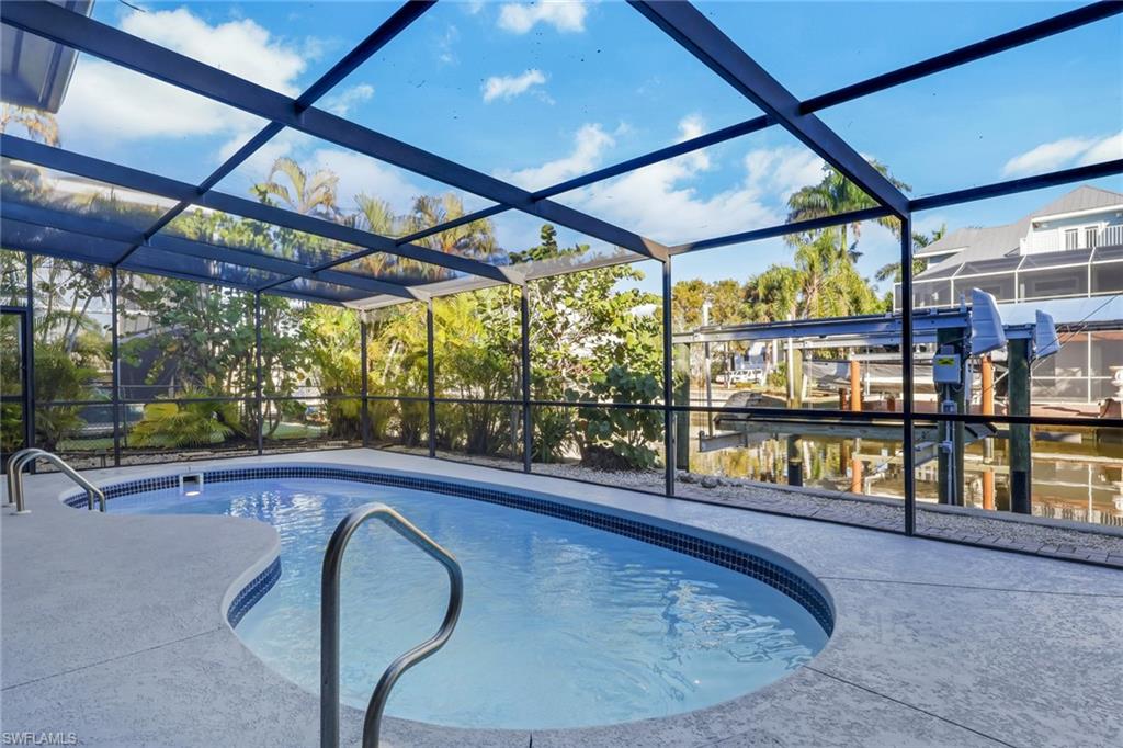 Outdoor pool featuring glass enclosure, a sunroom, and boat lift