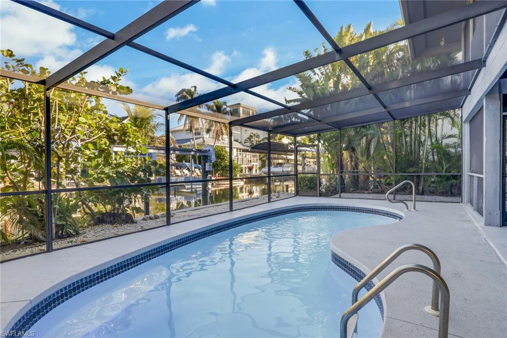 Outdoor pool featuring a sunroom, glass enclosure, and a patio