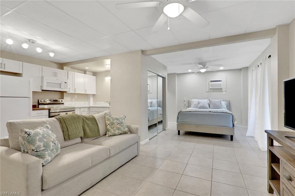 1/1 Efficiency-Bedroom with freestanding refrigerator, a paneled ceiling, a closet, light tile patterned floors, and a ceiling fan