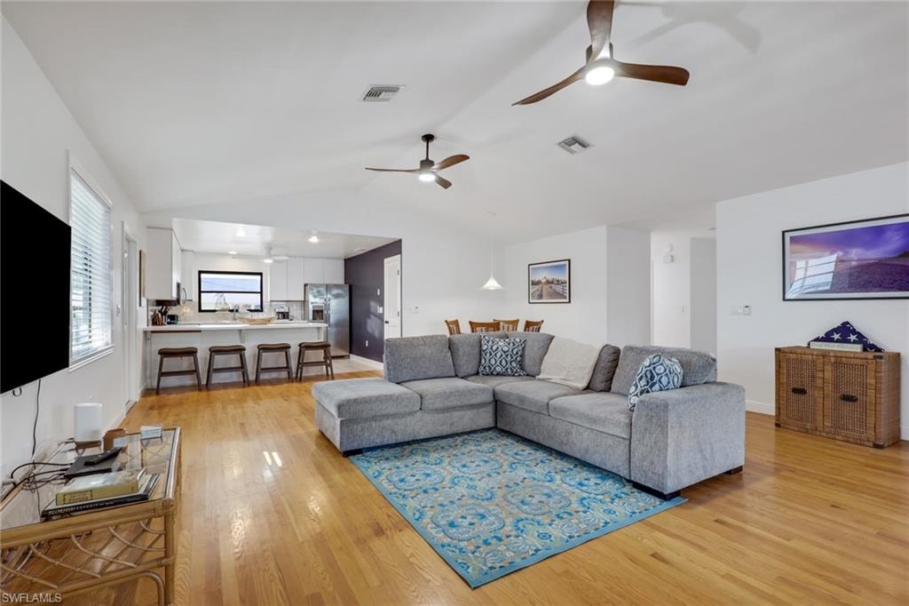 Living area featuring lofted ceiling, light wood-type flooring, and a ceiling fan