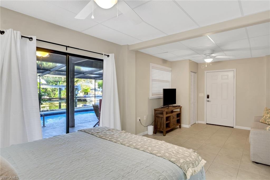 1/1 Efficiency-Bedroom with a ceiling fan, a sunroom, light tile patterned floors, access to exterior, and a drop ceiling
