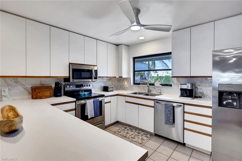 Kitchen with light countertops, stainless steel appliances, white cabinetry, light tile patterned floors, and recessed lighting