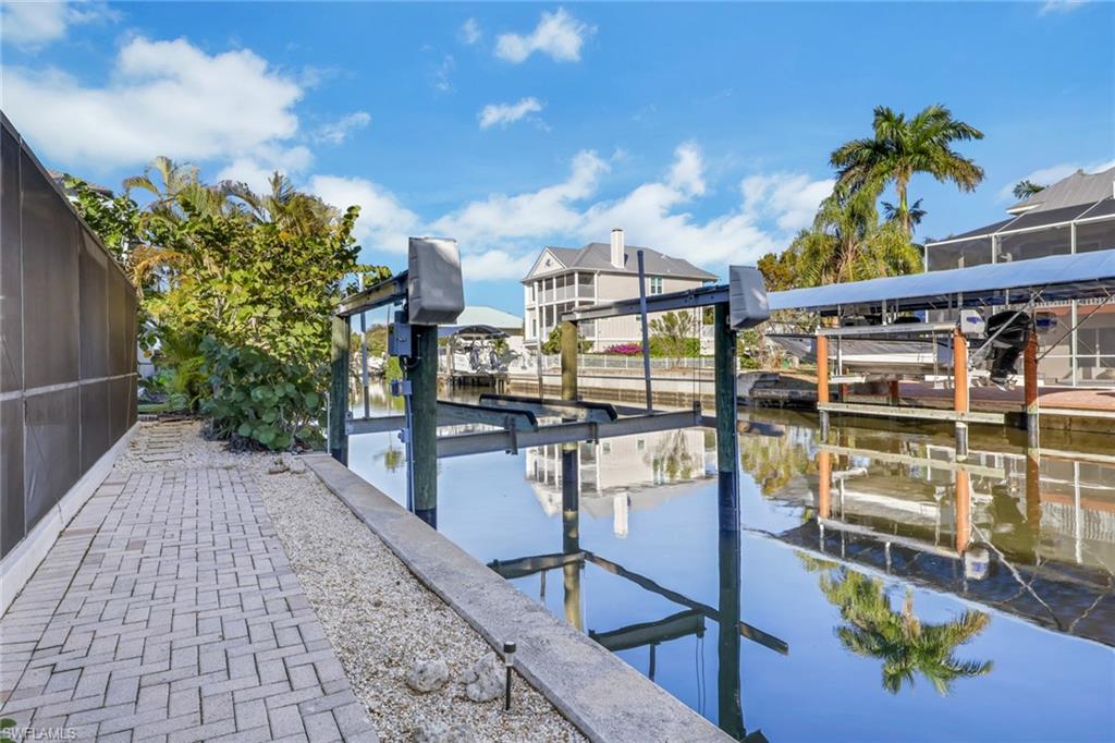 Dock area featuring glass enclosure, boat lift, and a water view