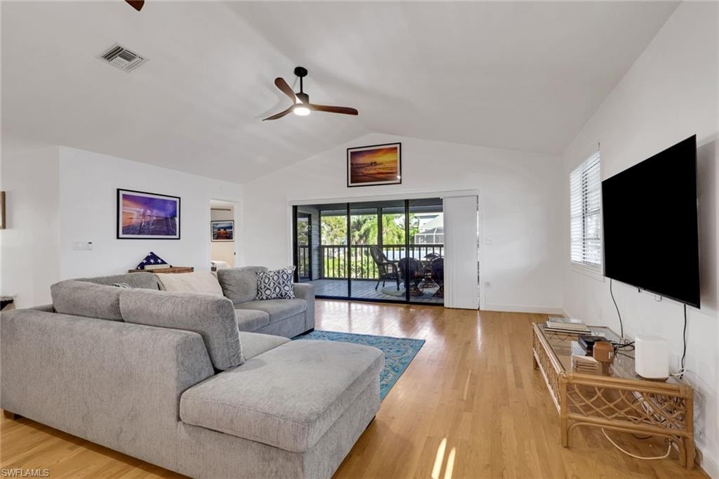 Living area featuring vaulted ceiling, plenty of natural light, light wood-style floors, and ceiling fan