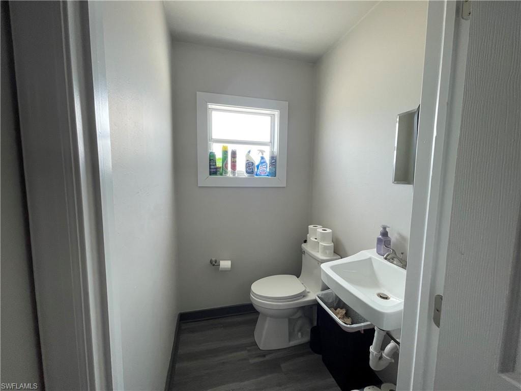 Half bathroom featuring toilet and dark wood-style flooring