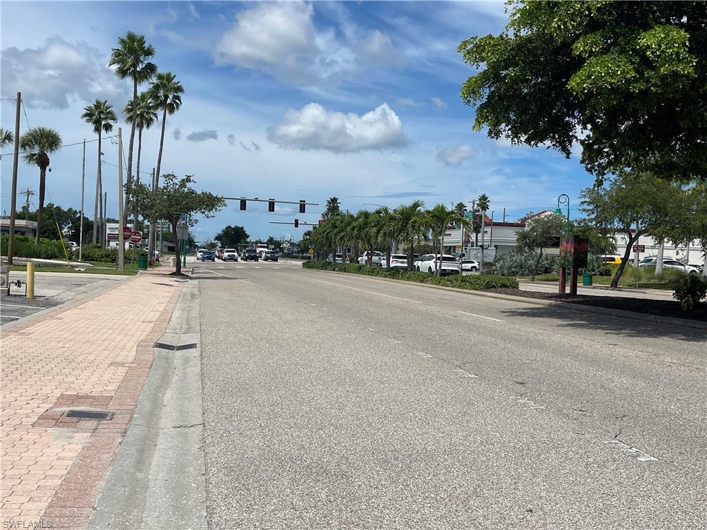 View of asphalt road featuring traffic lights, sidewalks, curbs, and street lighting