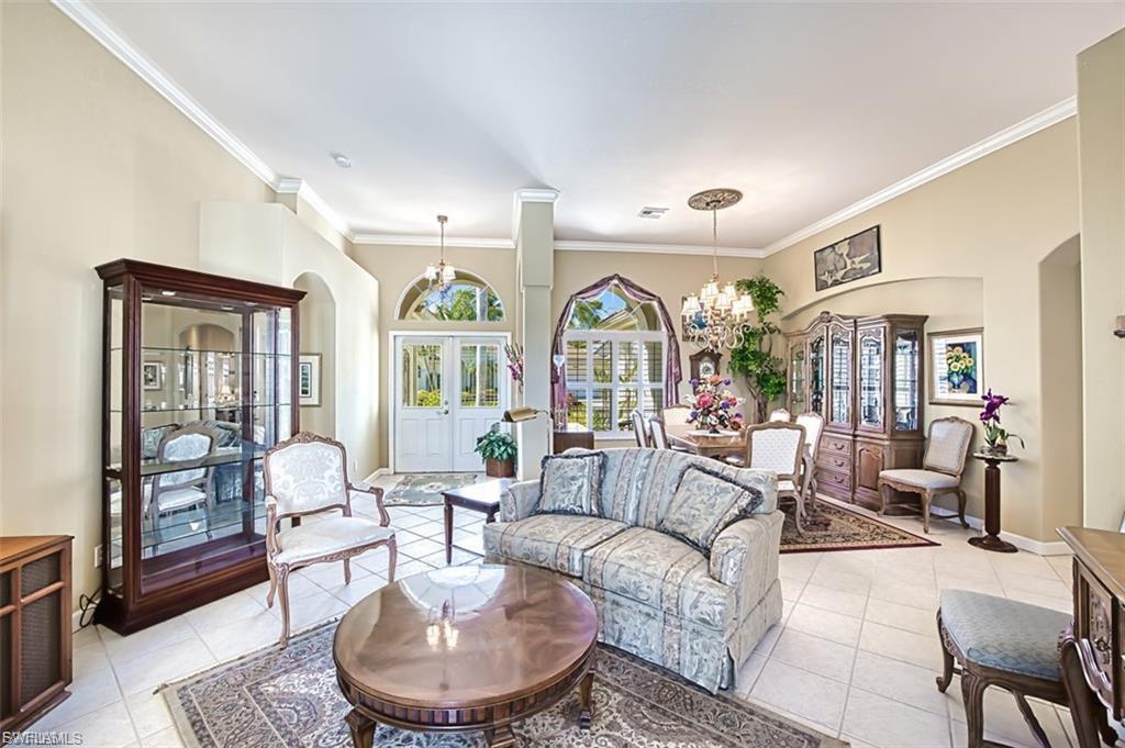 Living room featuring arched walkways, healthy amount of natural light, french doors, light tile patterned floors, and ornamental molding