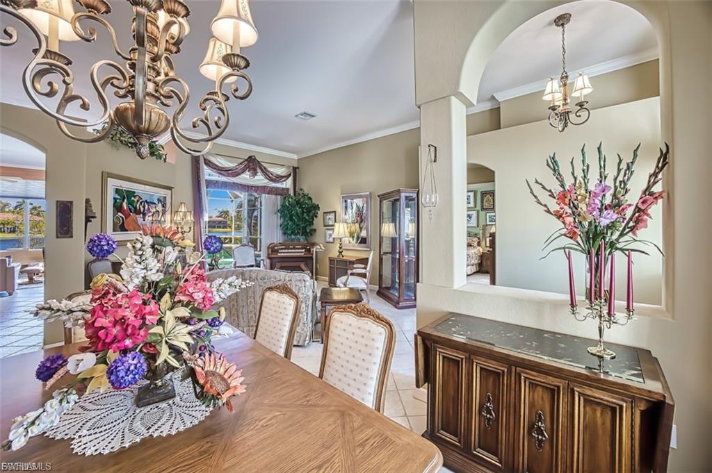 Tiled dining space with arched walkways, a chandelier, and ornamental molding