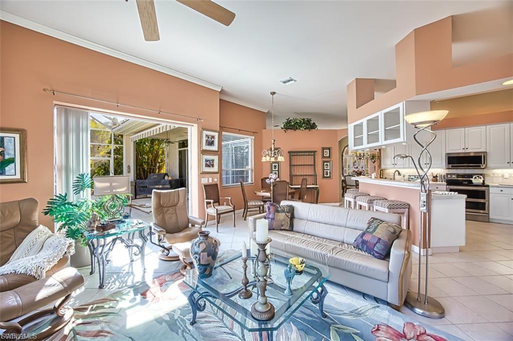 Living room with light tile patterned flooring, ceiling fan, and ornamental molding