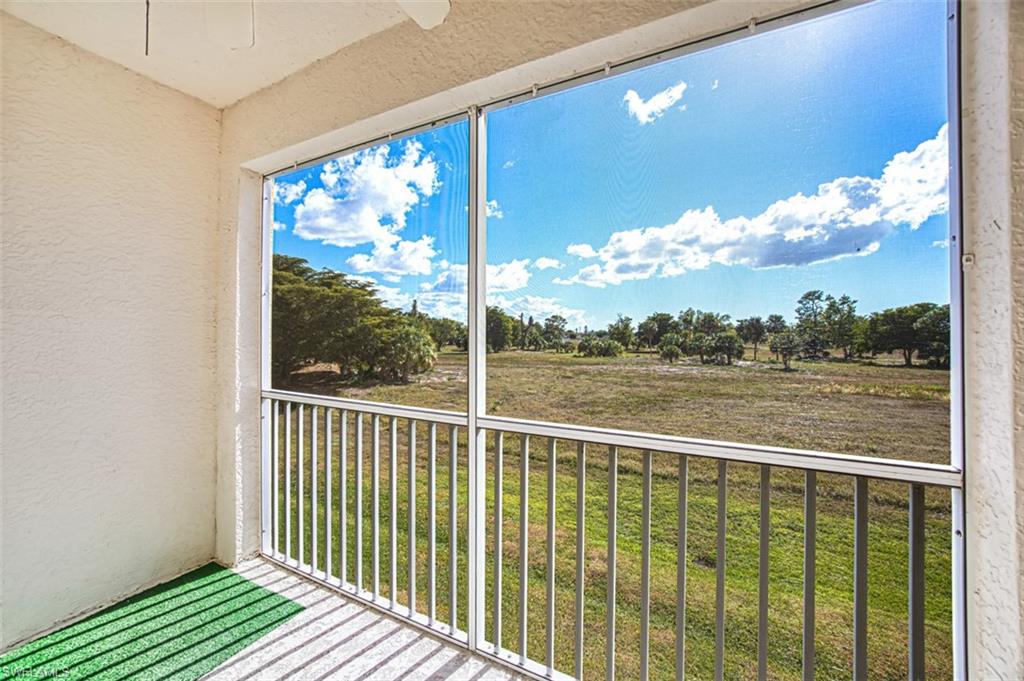 Balcony with a sunroom, ceiling fan, a rural view, and view of wooded area