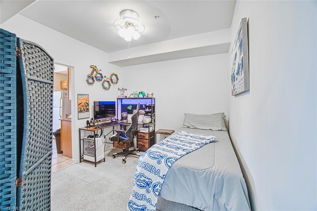 Carpeted bedroom with an office area and freestanding refrigerator