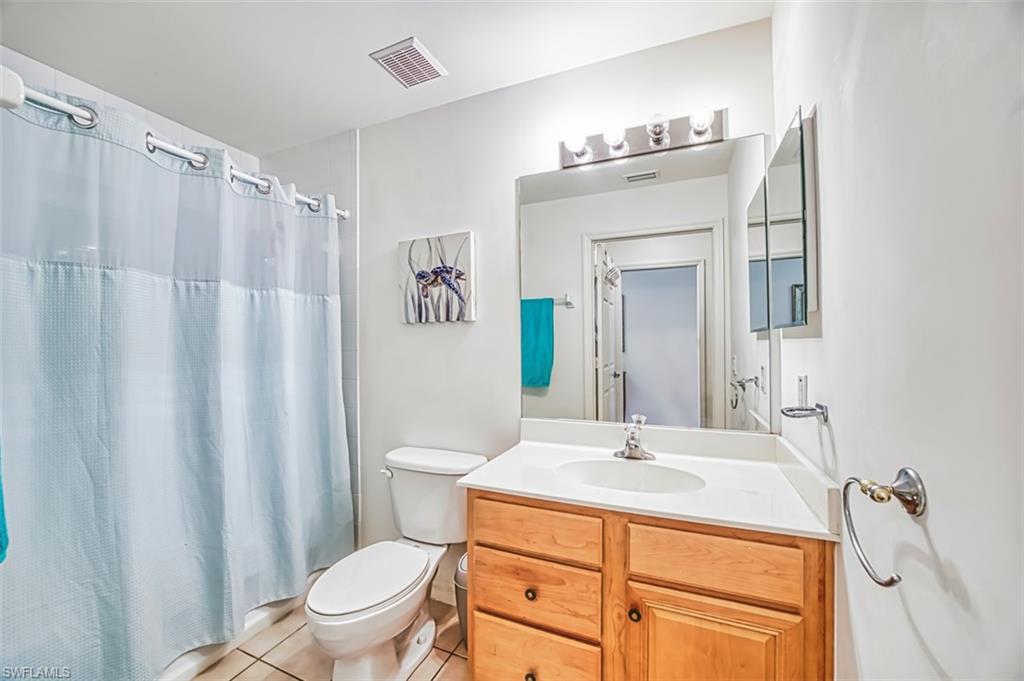 Bathroom with vanity, light tile patterned flooring, and shower / bathtub combination with curtain