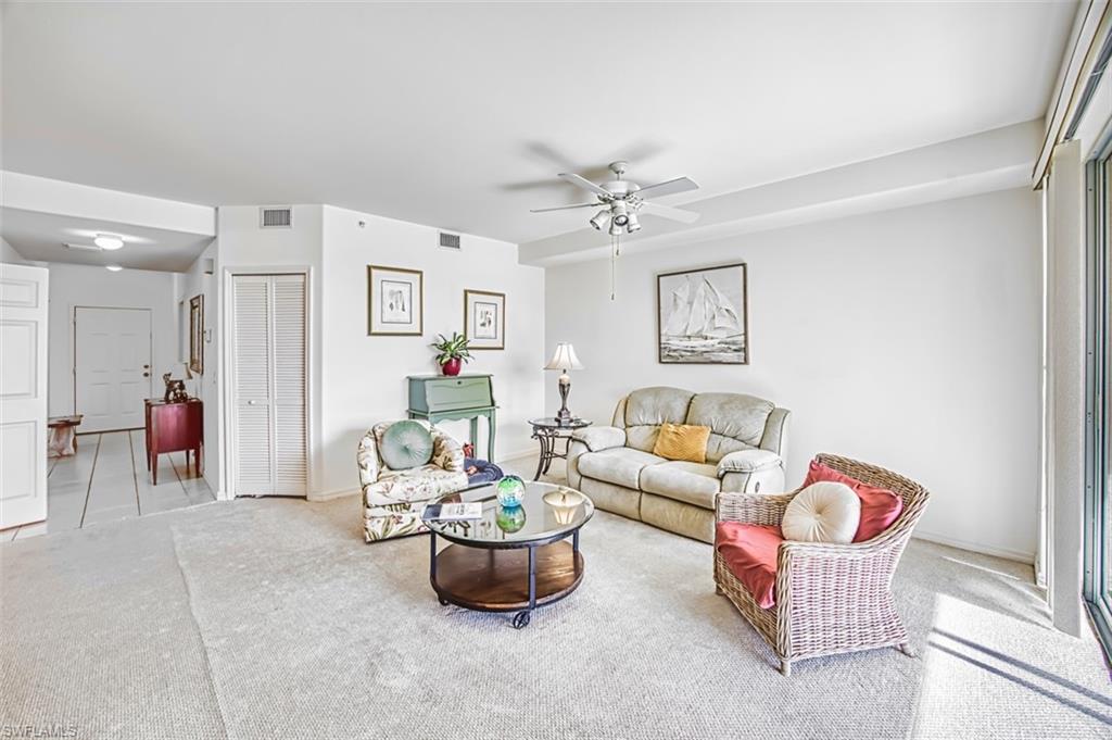 Carpeted living room with a ceiling fan