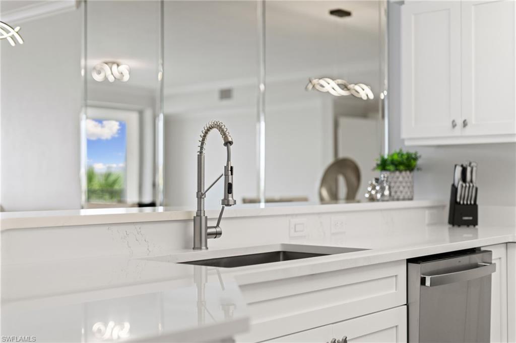 Kitchen featuring dishwasher, white cabinets, and light stone countertops