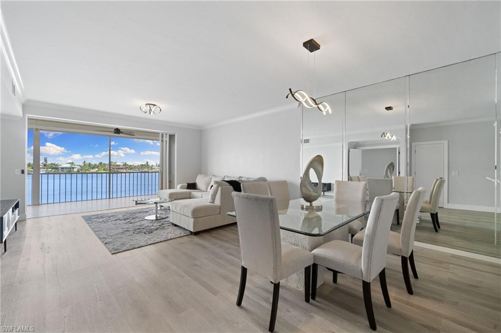 Dining space featuring ornamental molding, a water view, and light wood finished floors
