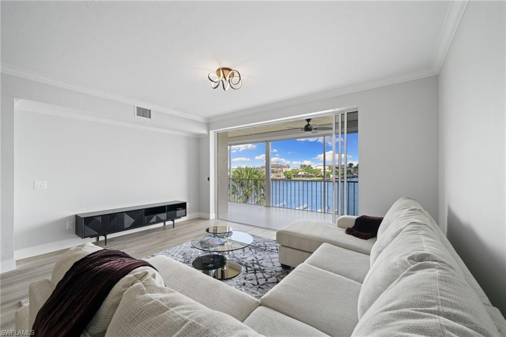 Living room with a water view, crown molding, and wood finished floors