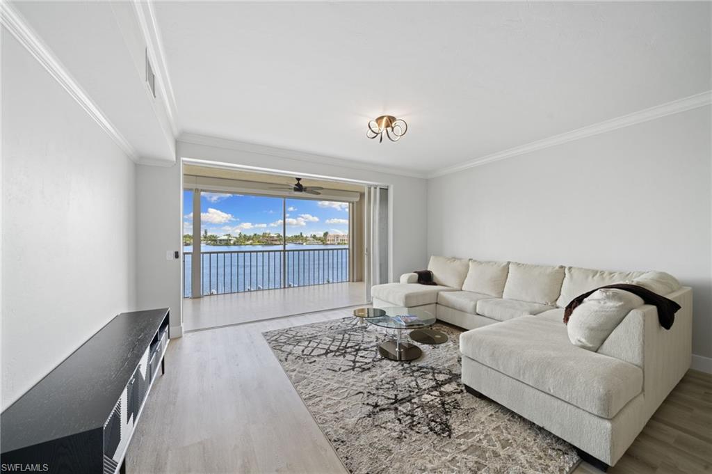 Living area with a water view, light wood finished floors, and crown molding
