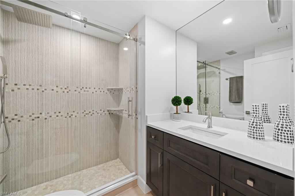 Bathroom with a shower stall, vanity, and recessed lighting