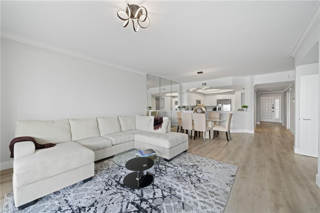 Living area with ornamental molding and light wood-style flooring