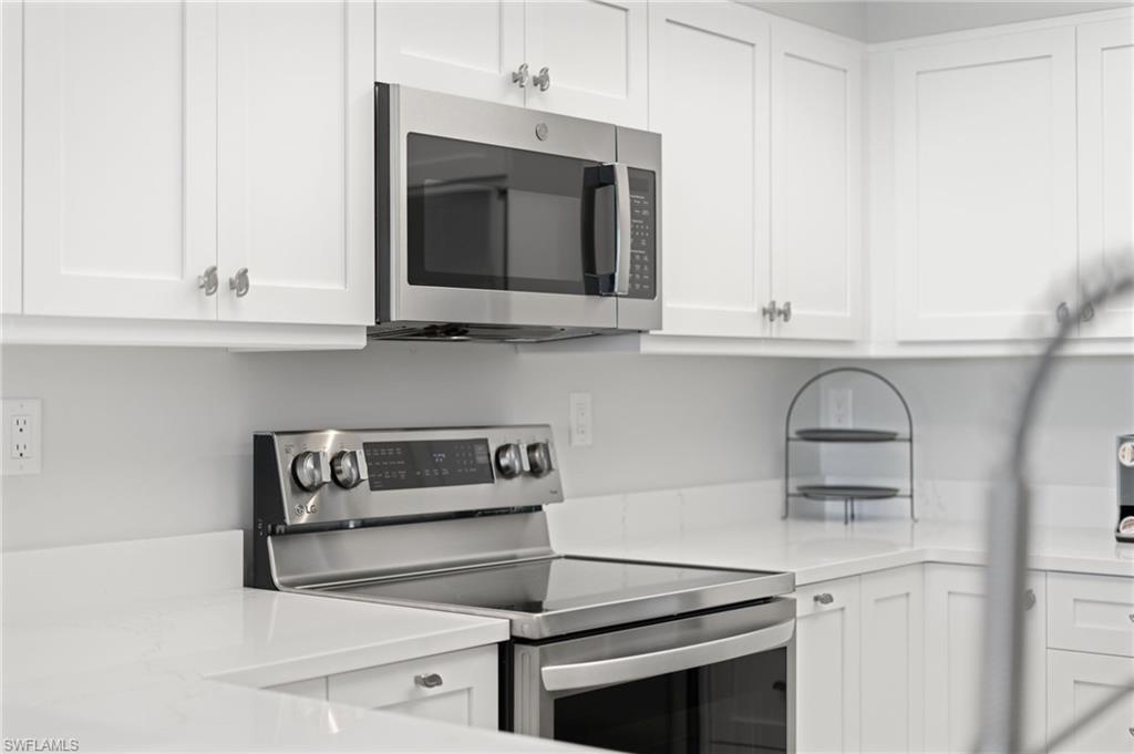 Kitchen with stainless steel appliances, white cabinets, and light stone countertops