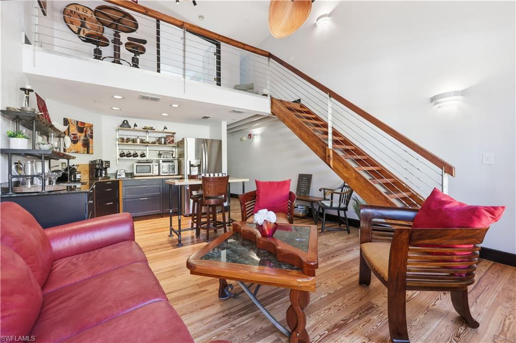 Living area with light wood-type flooring, a towering ceiling, and stairway