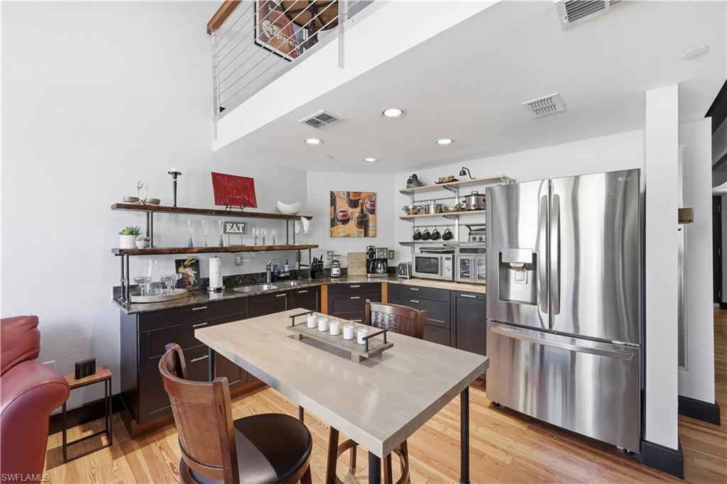 Kitchen with stainless steel fridge with ice dispenser, open shelves, light wood-style flooring, white microwave, and recessed lighting