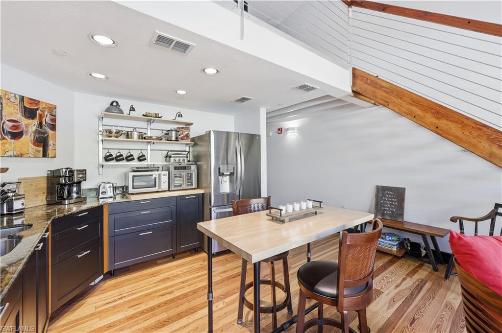 Kitchen featuring open shelves, dark stone countertops, stainless steel refrigerator with ice dispenser, and recessed lighting