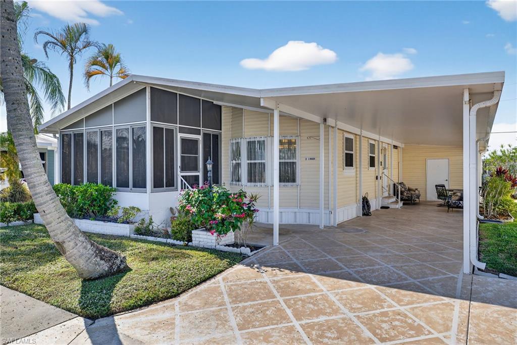 Manufactured / mobile home featuring an attached carport, a sunroom, a front yard, and entry steps
