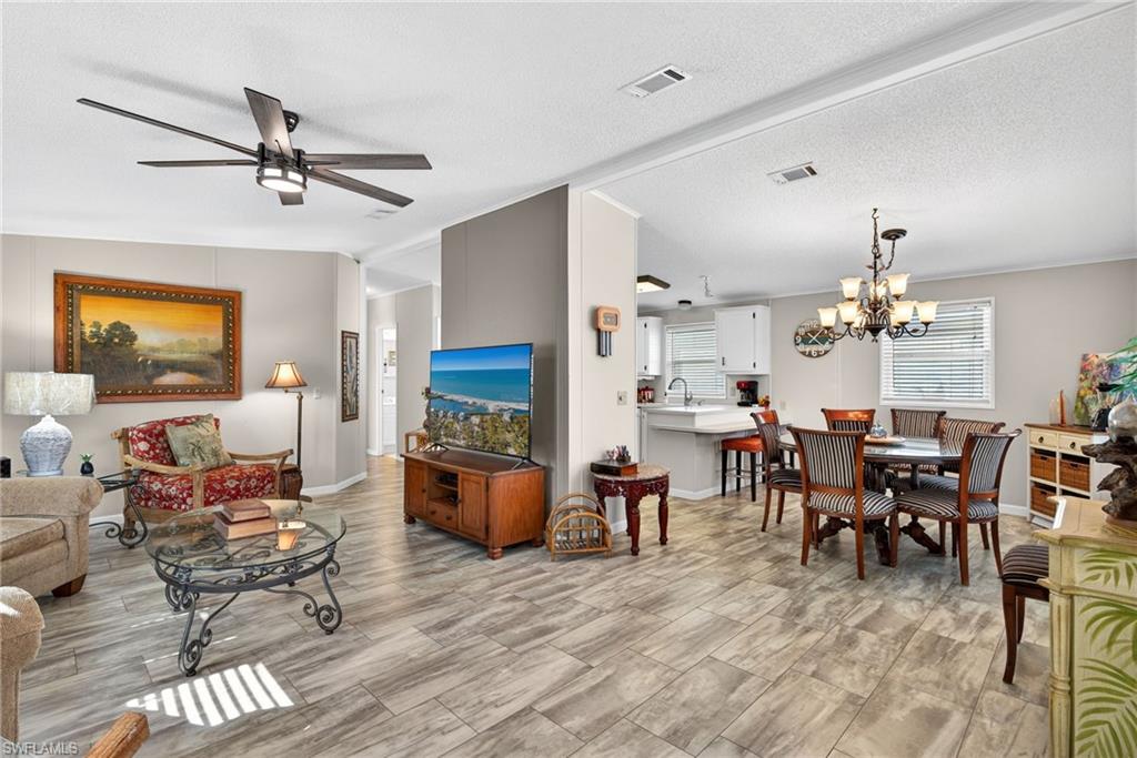 Living room featuring a chandelier, ceiling fan, and a textured ceiling