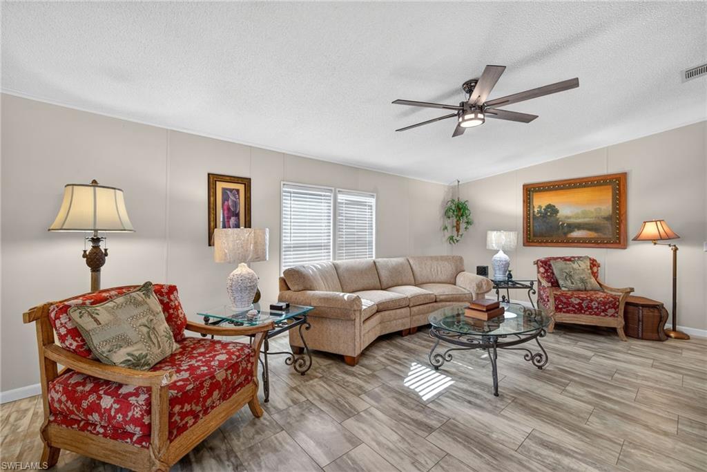 Living room featuring a ceiling fan, a textured ceiling, vaulted ceiling, and wood tiled floors