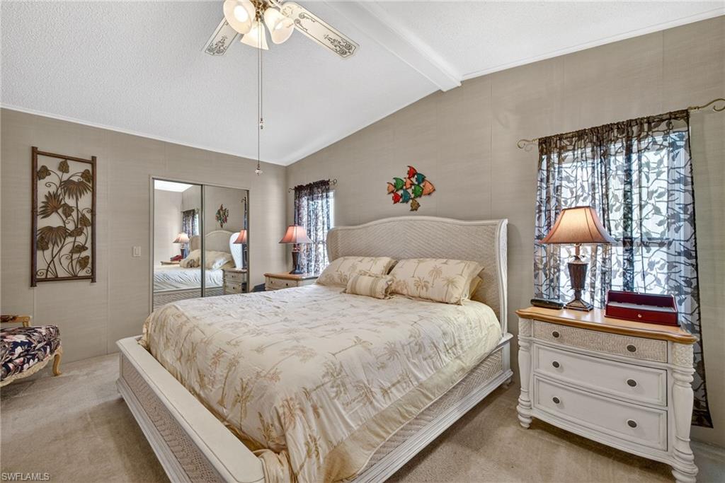 Bedroom with light carpet, a closet, ceiling fan, and a textured ceiling