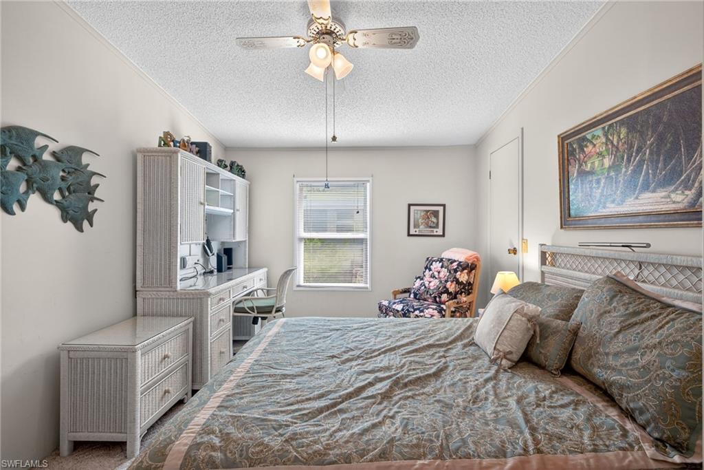Bedroom with a textured ceiling, an office area, ceiling fan, carpet, and ornamental molding