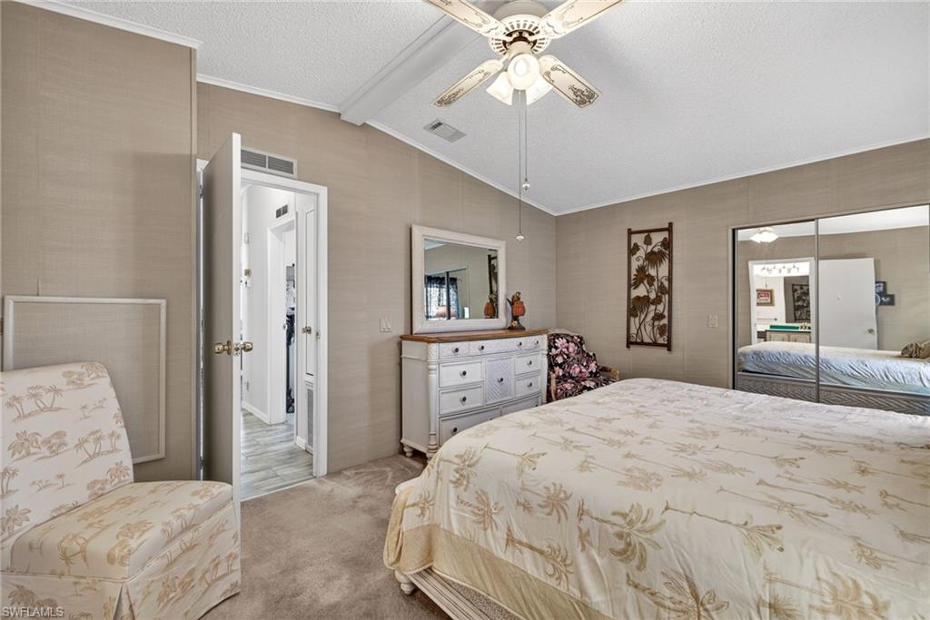 Carpeted bedroom featuring a textured ceiling, ceiling fan, a closet, and ornamental molding