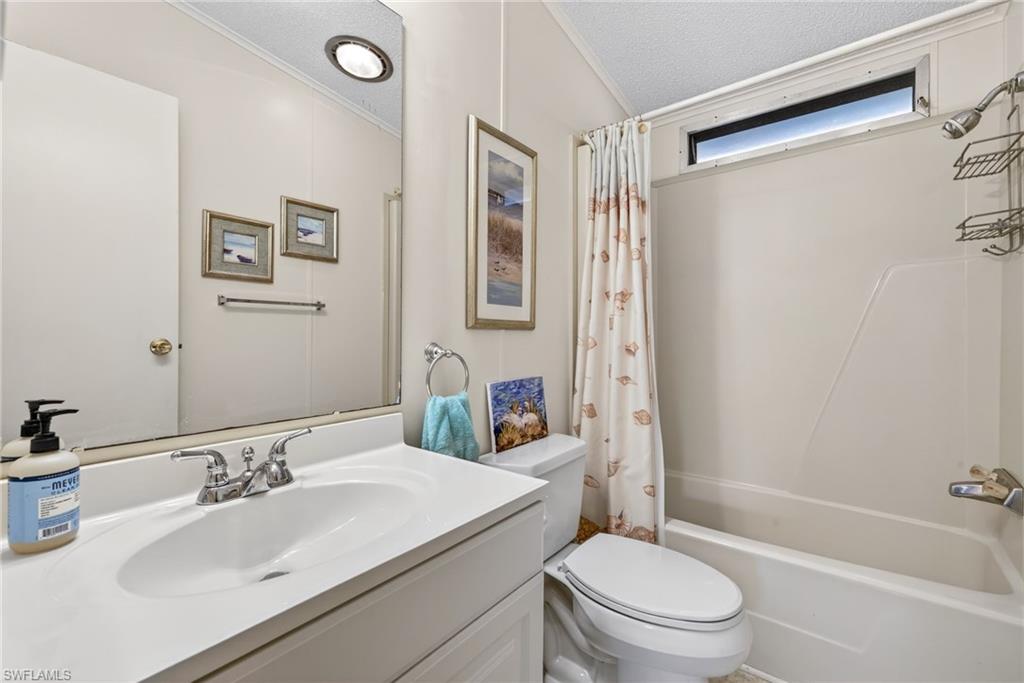 Bathroom with vanity, crown molding, shower / bath combo with shower curtain, and a textured ceiling