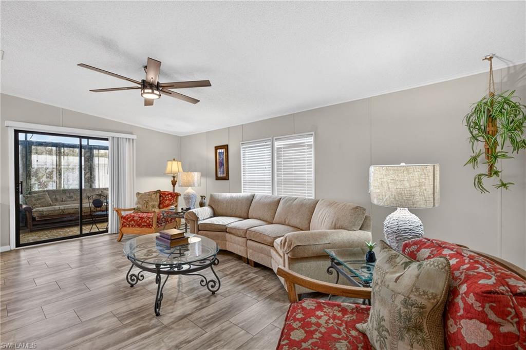 Living area with wood finish floors, a ceiling fan, lofted ceiling, and a textured ceiling