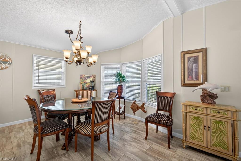 Dining space with a decorative wall, ornamental molding, a textured ceiling, a chandelier, and lofted ceiling