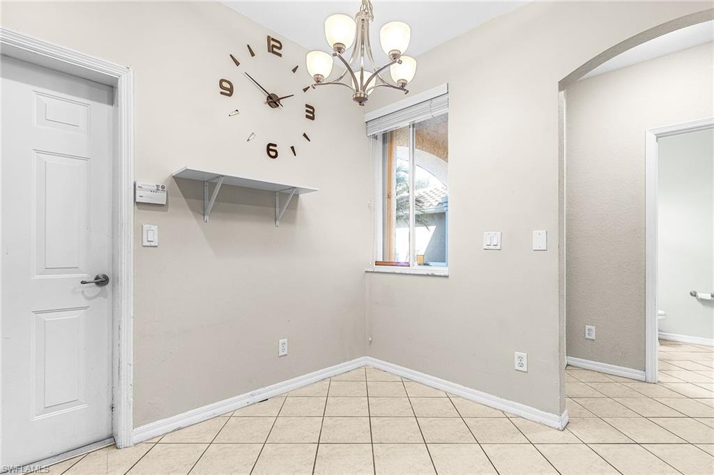 Unfurnished dining area featuring light tile patterned floors, a chandelier, and arched walkways