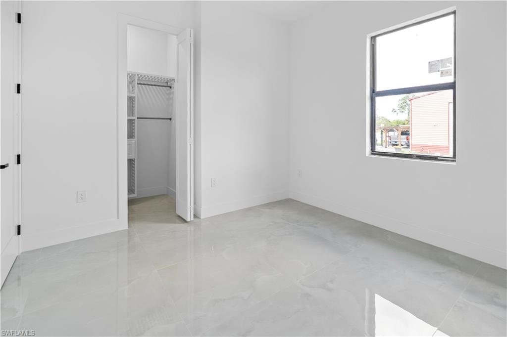 Unfurnished bedroom with baseboards and a spacious closet