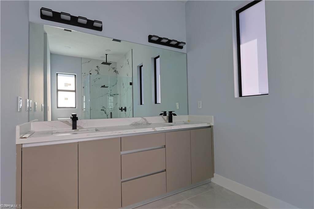 Full bath with a marble finish shower and double vanity