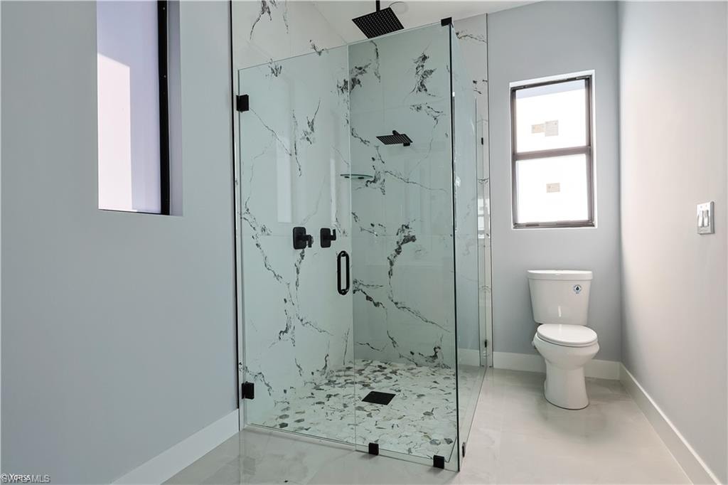 Full bath with a marble finish shower and marble finish floors