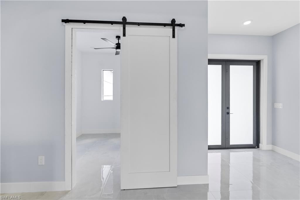 Spare room featuring a barn door, ceiling fan, and french doors