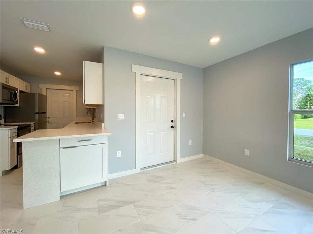 Kitchen featuring white cabinetry, appliances with stainless steel finishes, recessed lighting, light stone counters, and a peninsula