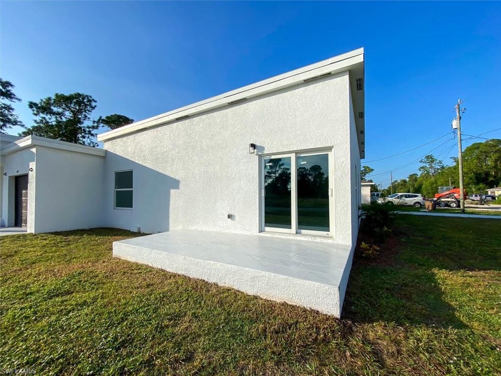 Back of property with a lawn, stucco siding, and a patio