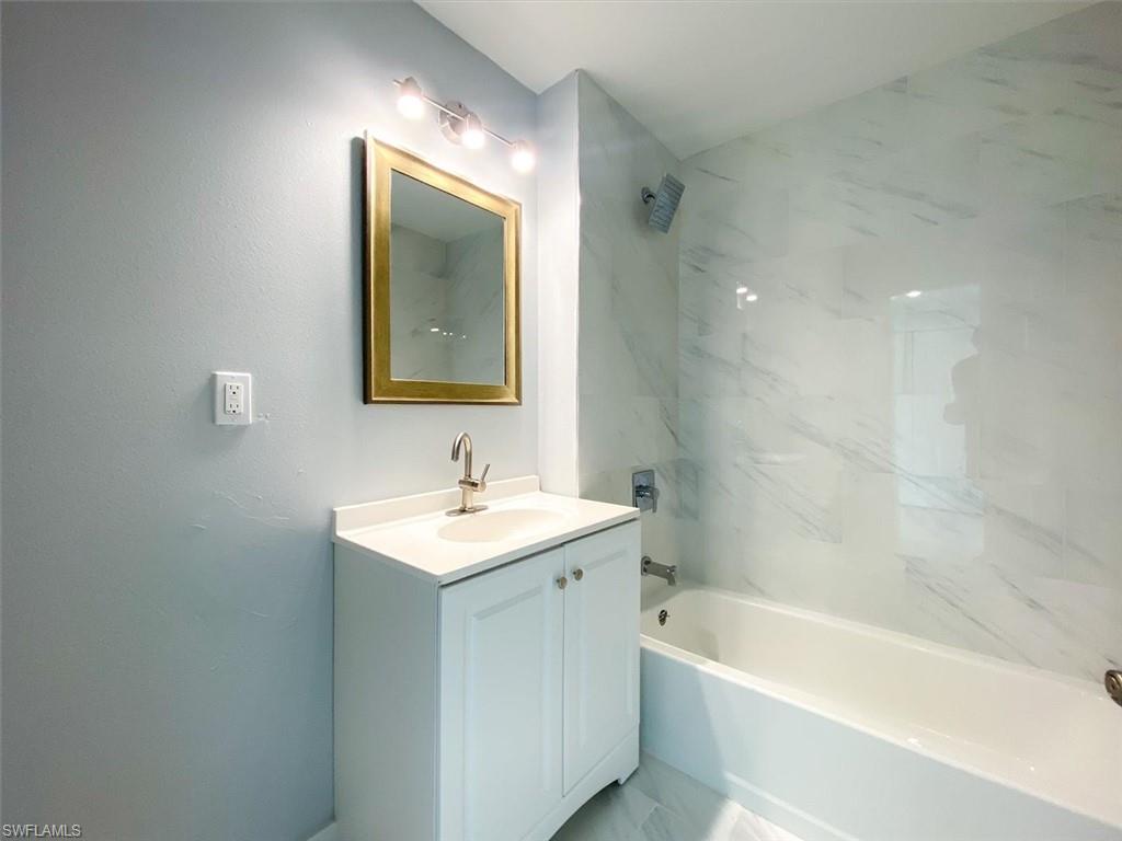Full bath featuring vanity, bathtub / shower combination, and light marble finish flooring